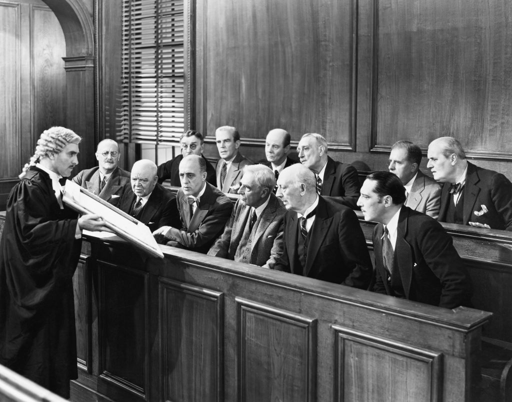 Schwarz-Weiß Bild, bei dem Personen in einem Gericht zu sehen sind.