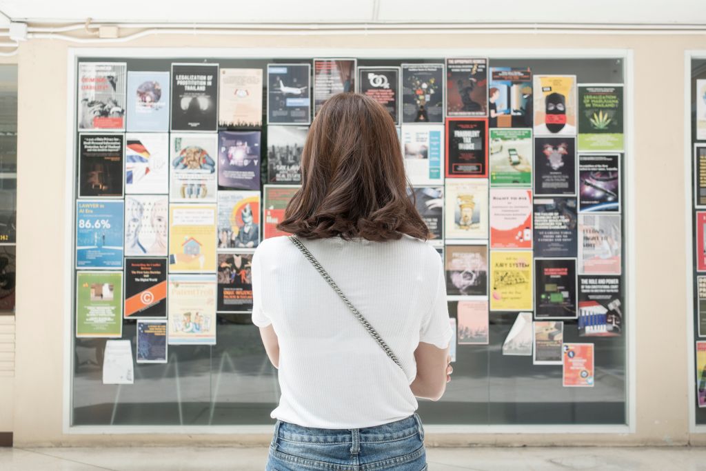 Eine Frau betrachtet eine Wand mit Plakaten.