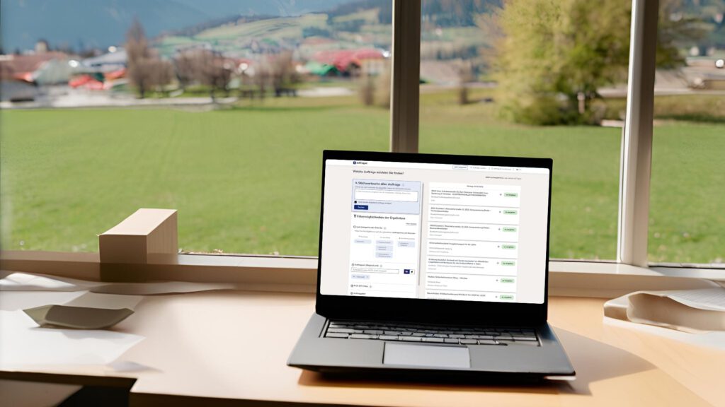 Laptop mit geöffneter auftrag.at-Suche mit österreichischer Landschaft im Hintergrund